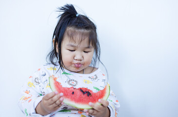 A cute little Asian girl is happily eating watermelon,lovely little asian girl eating watermelon on white background,cute little asian girl in chinese traditional dress and eating watermelon on white 