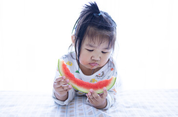 A cute little Asian girl is happily eating watermelon,lovely little asian girl eating watermelon on white background,cute little asian girl in chinese traditional dress and eating watermelon on white 