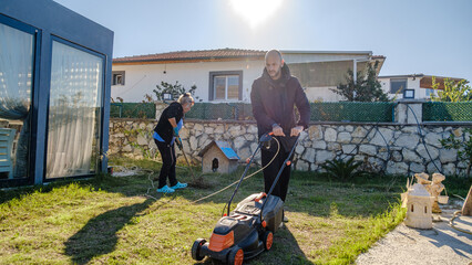 A mother and her middle-aged son working together on garden maintenance in their garden on a winter day