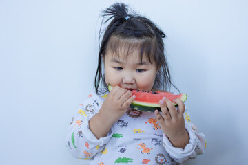 A cute little Asian girl is happily eating watermelon,lovely little asian girl eating watermelon on white background,cute little asian girl in chinese traditional dress and eating watermelon on white 