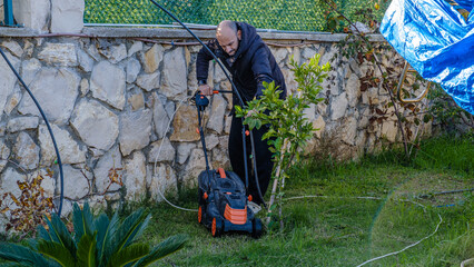 A middle-aged man mowing the grass in his garden with a lawnmower on a winter day
