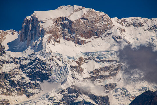 Snow-covered slopes of Ngadi Chuli (7,871 meters), also known as Peak 29, part of the Manaslu Himal range in Nepal. Dramatic Himalayan mountain landscape with glaciers, layered rock faces and drifting