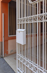 Mailbox Hanging at White Gate Metal Fence House Exterior