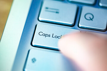 Close-up computer keyboard keys and finger, top view.