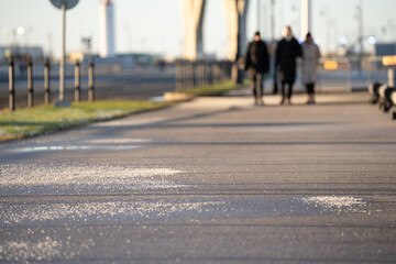 Technical salt scattered over asphalt ground surface for ice crust formation prevention and traffic...