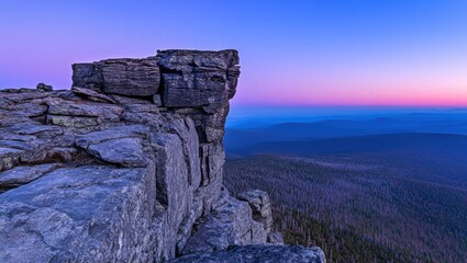 Rocky summit overlooking a vast landscape at dawn.