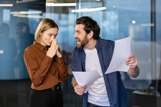 Angry male boss yelling at a stressed female employee holding her hands together. Creating an uncomfortable and toxic work environment portraying workplace conflict. Bullying. Pressure. And harassment