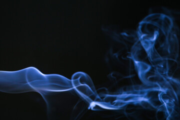 Abstract blue smoke swirling gracefully against a dark background, evoking a sense of mystery and movement