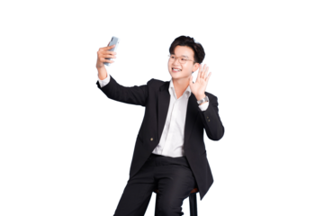 Smart Casual Greetings: An individual in smart casual attire, sits and takes a selfie, waving towards the phone with a smile.