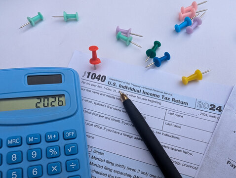 tax 2026 with irs form 1040, calculator, pen, and push pins