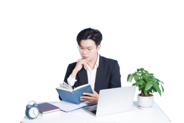 Thoughtful Reading: A focused individual, absorbed in the pages of a book, surrounded by the tools of the modern workplace, a symbol of intellectual engagement.