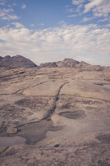 Wide-angle view of a desolate, weathered granite plateau under a blue sky with scattered clouds.