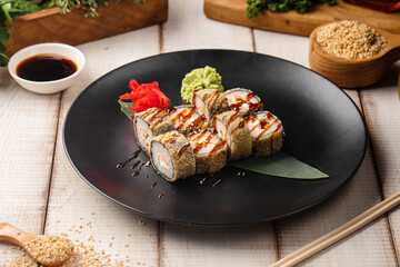 Fried sushi rolls with fish cream cheese and rice topped with sauce and sesame served on a black plate © Hihitetlin
