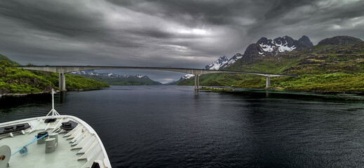 Cruise Ship Approaches High Bridge Over Calm Fjord Near Stokmarknes At The Lofoten In Norway