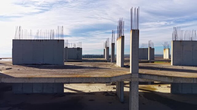 Empty concrete pillars rise into the air at a forsaken building site, showcasing the stark beauty of unfinished architecture with the horizon stretching far and wide.