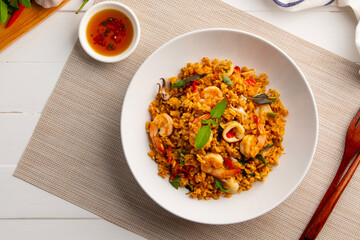 Seafood Tom Yum Fried Rice,Stir fried rice with shrimp and squid with chilli sauce on white plate.Top view.