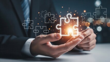 Professional hands in a dark suit gently cradling glowing, interconnected white outline puzzle pieces with a warm orange center, illuminated by soft bokeh lights in a modern office setting,