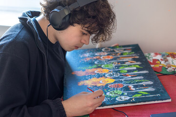 Teenage boy painting a colorful artwork at home, creative hobby, focused adolescent artist working on canvas indoors © Светлана Мищенко