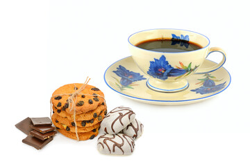 Elegant vintage teacup with assorted sweets and biscuits.
