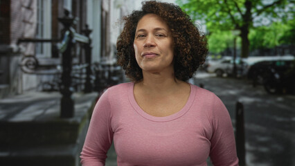 Woman pressing lips closed with finger lifted forward in urban street setting, middle age hispanic...