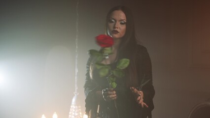 Gothic femme fatale in black godet dress and corset, dark elegant interior.