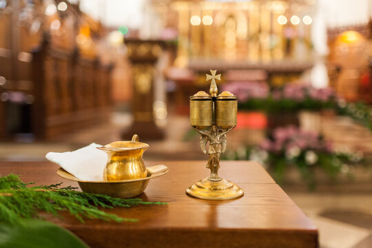 Baptism liturgical ampoules, holy water bowl and angel-shaped chrism vessel,old style religious art on a blurred church background.FF DSLR 