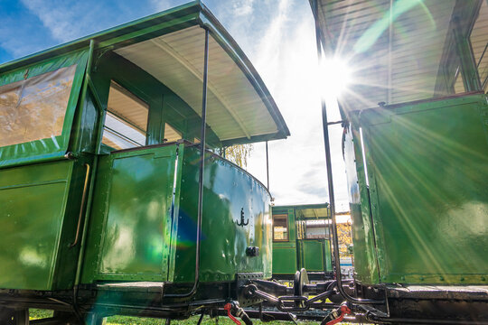 Green train car sits on tracks under bright sunlight in a rail yard, showcasing its vintage design and sturdy construction