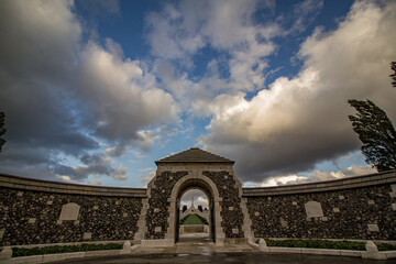 Tyne Cot Cemetery and Memorial under dramatic storm clouds in Zonnebeke, Belgium. Largest WWI Commonwealth military burial ground with white headstones and Cross of Sacrifice in Flanders.