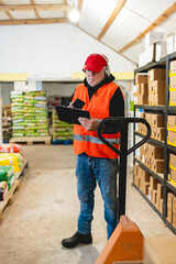 An older worker in a pet food warehouse prepares deliveries of goods for pet stores.Cheerfully does his job.