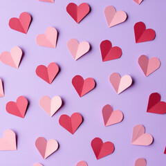 Small paper hearts scattered on a pastel lavender background. Flat lay composition with soft pink and muted red paper hearts, even studio lighting, clean minimal surface, and clear copy space.