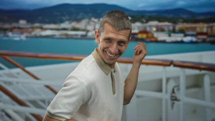 Man smiling and posing playfully as if playing guitar on a cruise ship with a coastal city view in the background, capturing a fun outdoor moment on the sea.