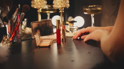 Silhouette woman sitting at makeup table with mirror various natural cosmetics lipstick lip gloss, gold color shiny case, glamour makeup. sexy girl preparing makeup. black night dark room background