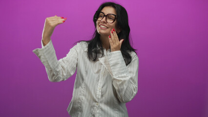 Woman wearing glasses and white shirt cupping hands near mouth while gesturing in purple studio; communication enthusiasm.