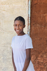 village african young girl teenager, with braids hairstyle , outdoors in the nature, at home , in front of the house wall