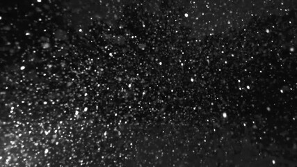 Particles falling and floating in black space with bokeh effect creates a cosmic vibe