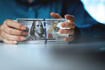 A person is holding a stack of $100 bills