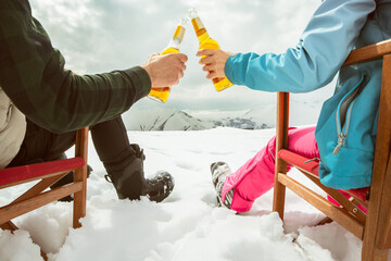 Couple relax sit on chairs in snowy ski resort with beer bottle, concept of leisure, winter holiday, relaxation, carefree lifestyle, freedom, cozy outdoor relaxation moment