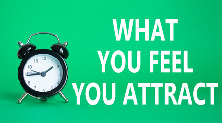 What you Feel you Attract you symbol. Wooden blocks with words What you Feel you Attract. Beautiful green background with alarm clock. Business and What you Feel you Attract concept. Copy space.