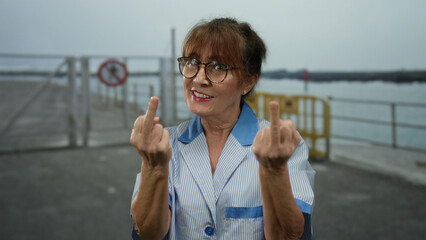 Woman smiling seaside promenade middle finger gesture cleaner glasses outdoor beach hispanic senior.