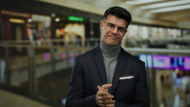 Young man clapping in a modern mall setting, creating a dynamic scene of gesture and emotion in an indoor shopping environment.