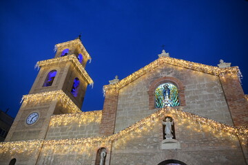 Church facade and tower in Torrevieja decorated with holiday lights
