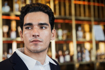 Portrait of businessman standing at hotel lounge. Handsome young people with vision looking away. Joining the corporate event. Relaxing in the party