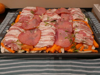 Prepared fish and salmon wrapped in bacon on carrots and fennel with dill on baking tray. Oven dish. Copyspace.