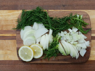 Kitchen ingredients for fish dish onions dill lemon on wooden board.  Ingredients for fish dish. Copyspace.