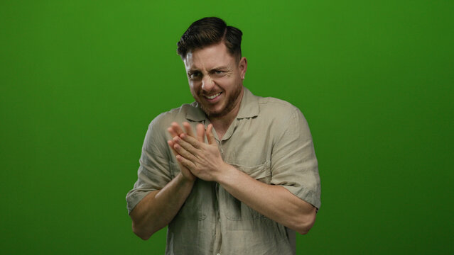Young man with beard expresses emotion against isolated green background wearing casual shirt.