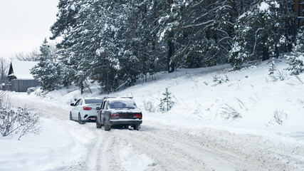 Traffic after a snowfall. A trip out of town. Two cars are spinning in a snow rut on the highway.