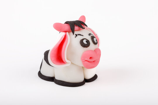 Cute handmade marzipan cow figurine for cake decoration isolated on white background.