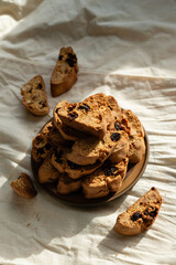 Stack of italian biscotti cantuccini cookies with nuts and raisins on a plate over white linen tablecloth