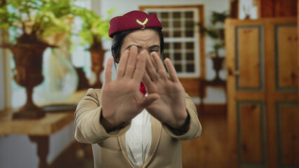 Woman in flight attendant uniform expressing fear with hands in a cozy living room setting, hinting...