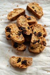 Italian cantuccini biscotti with nuts and dried fruits served on a white linen cloth with scattered ingredients